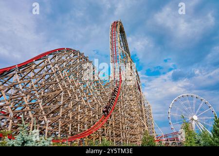 People riding at roller coaster attraction in amusement park. Entertainment at summer holiday Stock Photo