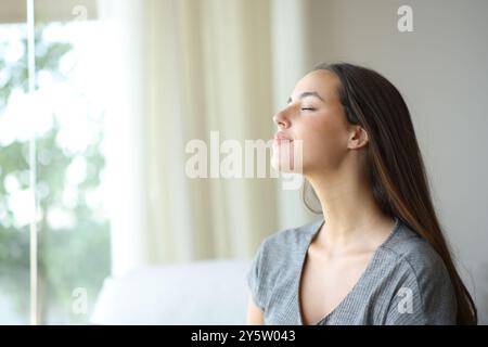 Woman breathing fresh air sitting on a sofa at home Stock Photo
