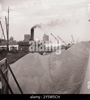 America of the 1940s. Unloading bauxite from a barge onto a Canadian boat which has come up through the inland waterways from Dutch Guiana. Oswego, New York. June 1943 Stock Photo