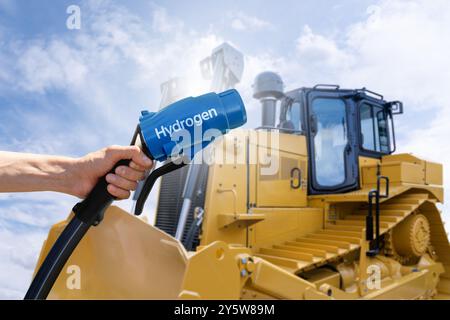 Hand with hydrogen fueling nozzle on a background of fuel cell construction machines. Concept.. Stock Photo