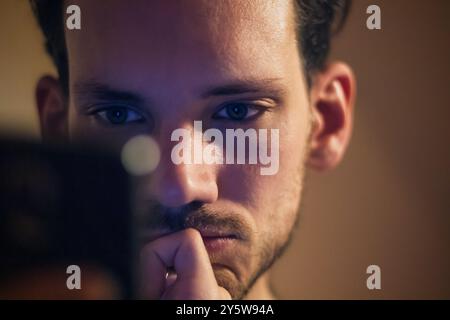 Closeup of a caucasian man engrossed in using mobile phone device. Mobile phone addiction. Stock Photo