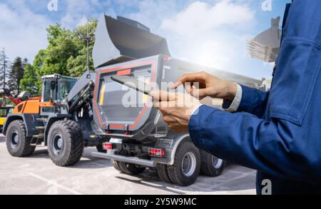 Hands with a digital tablet on the background of construction machines.. Stock Photo