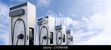 Row of electric vehicles charging stations on the background of blue sky. Stock Photo
