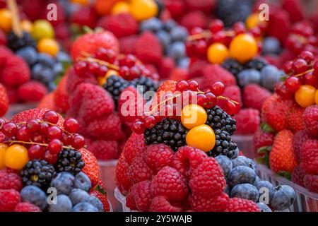 Baskets with fresh juicy berries on street market. Berries background (raspberry, blueberry, strawberry, red currant, blackberry, golden berry). Stock Photo