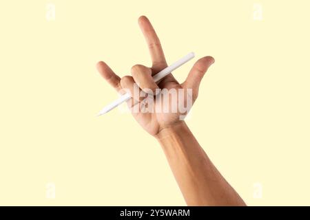 Male hand holding an smart pencil and doing the rock sign isolated on yellow background Stock Photo