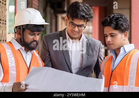 A serious meeting of an architect wi client, and a team of BMS, electrical, and civil engineers deeply engaged in reviewing and discussing a comprehend Stock Photo
