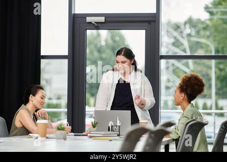 Three stylish businesswomen engage in a collaborative discussion at a contemporary office. Stock Photo
