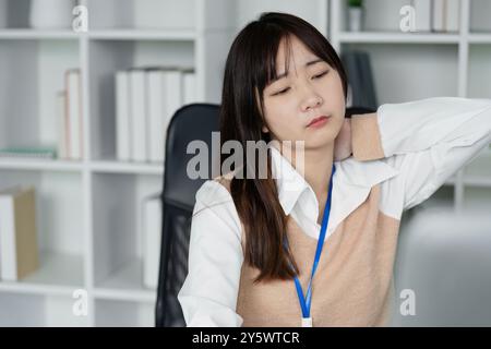 Office Worker Feeling Unwell at Desk, Experiencing Neck Pain and Discomfort in Modern Office Environment Stock Photo