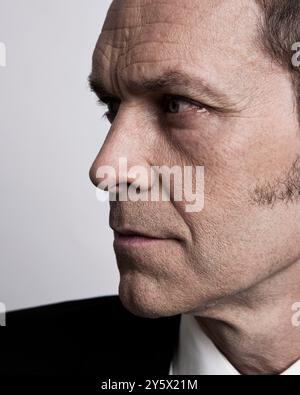 Close-up of a mature man in a suit looking to the side with a focused expression. Stock Photo