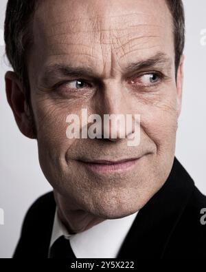 Close-up portrait of a smirking man in a black jacket against a white background. Stock Photo