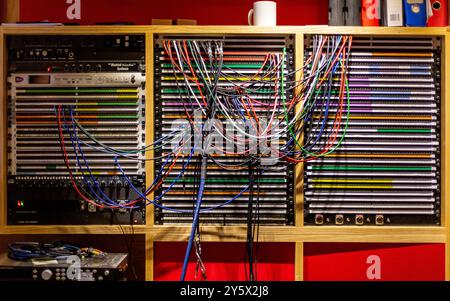 A complex network of colorful audio cables connected to equipment in a recording studio. Stock Photo