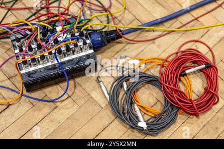 Audio cables and patch bay on a wooden floor in disarray. Stock Photo