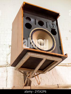 Vintage wooden speaker mounted on a wall with visible components and wires. Stock Photo