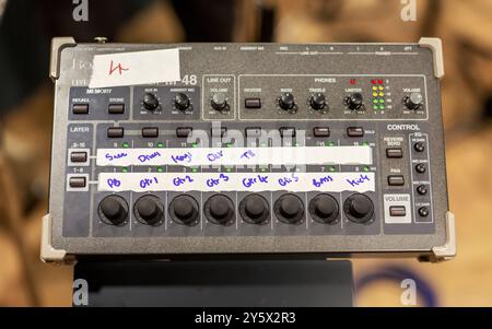 Audio mixing console with multiple adjustment knobs and channel inputs marked with handwritten labels. Stock Photo