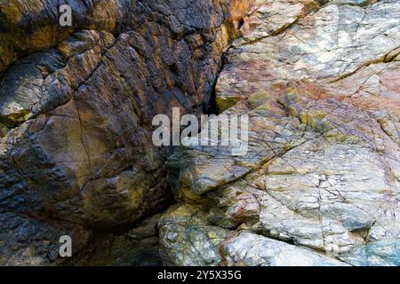Dark and light rocks on a cliff face separated by a diagonal crack. Stock Photo