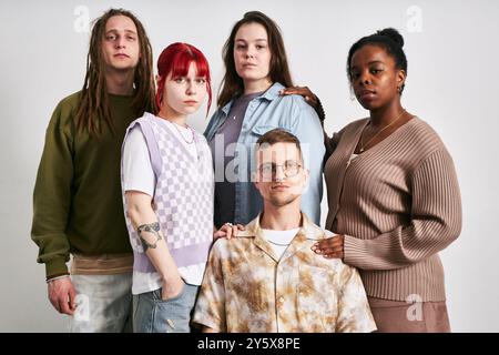 Portrait of group of five young adults of diverse ethnic backgrounds standing together against neutral background, showcasing various styles and personalities Stock Photo