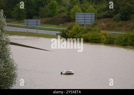 The open boot of a car is visible above the water where the vehicle is submerged in flood water on the A421 in Marston Moretaine, Bedfordshire. Parts of Britain have been struck by flash floods after some areas saw more than a month's worth of rain in 24 hours. Heavy rainfall has seen parts of Northamptonshire, Bedfordshire and London submerged causing widespread travel disruption and damage to properties. Picture date: Monday September 23, 2024. Stock Photo