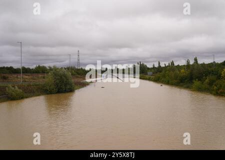 The open boot of a car is visible above the water where the vehicle is submerged in flood water on the A421 in Marston Moretaine, Bedfordshire. Parts of Britain have been struck by flash floods after some areas saw more than a month's worth of rain in 24 hours. Heavy rainfall has seen parts of Northamptonshire, Bedfordshire and London submerged causing widespread travel disruption and damage to properties. Picture date: Monday September 23, 2024. Stock Photo