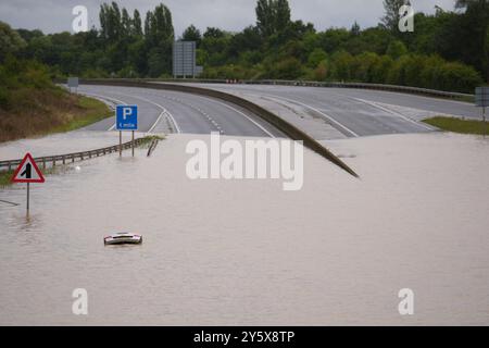 The open boot of a car is visible above the water where the vehicle is submerged in flood water on the A421 in Marston Moretaine, Bedfordshire. Parts of Britain have been struck by flash floods after some areas saw more than a month's worth of rain in 24 hours. Heavy rainfall has seen parts of Northamptonshire, Bedfordshire and London submerged causing widespread travel disruption and damage to properties. Picture date: Monday September 23, 2024. Stock Photo