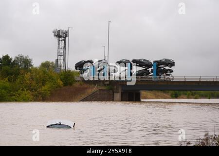 The open boot of a car is visible above the water where the vehicle is submerged in flood water on the A421 in Marston Moretaine, Bedfordshire. Parts of Britain have been struck by flash floods after some areas saw more than a month's worth of rain in 24 hours. Heavy rainfall has seen parts of Northamptonshire, Bedfordshire and London submerged causing widespread travel disruption and damage to properties. Picture date: Monday September 23, 2024. Stock Photo