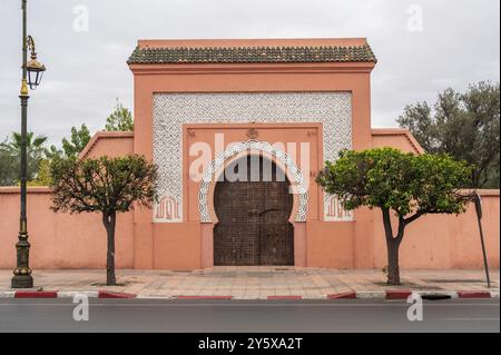 Wooden door in Marrakesh, Morocco. Moroccan closed archway gate in stone terracotta wall with islamic ornaments Stock Photo