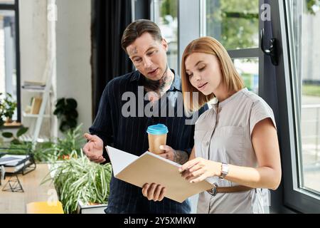Two young professionals are reviewing documents together while discussing ideas in the office. Stock Photo
