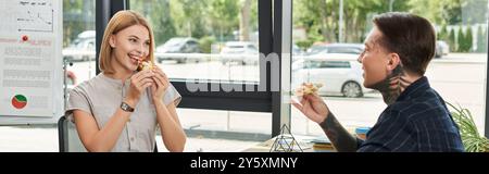 Two colleagues share a light hearted moment while eating pizza together at work. Stock Photo