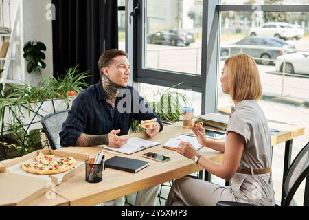 Two colleagues share a pizza and engage in friendly conversation during their lunch break. Stock Photo