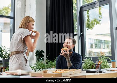 Two coworkers enjoy a lighthearted lunch break, sharing food and laughs in their workspace. Stock Photo