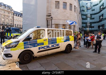 London, UK. 21st September, 2024. A small group of pro-Israel counter-protesters stands behind a Metropolitan Police vehicle to observe protesters gathered close to the headquarters of the BBC to criticise the broadcaster's coverage of Israel's attacks on Lebanon over the past week. Credit: Mark Kerrison/Alamy Live News Stock Photo