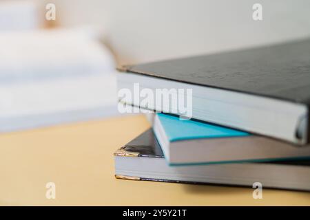 Close-up of a stack of books on a wooden desk, ideal for education and study themes, symbolizing learning and knowledge. Stock Photo