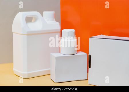A selection of white plastic bottles and cardboard boxes displayed against a bright orange backdrop, showcasing packaging and storage solutions. Stock Photo