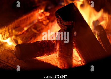 A close shot of a campfire at night, with active dancing flames and orange glowing embers. Stock Photo