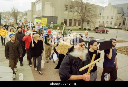 Anti-war protesters march through Bloomington, Indiana, carrying signs and symbols of peace during a demonstration against the U.S. involvement in the wars in Afghanistan and Iraq. Participants hold crosses, peace signs, and banners calling for an end to violence, reflecting widespread opposition to the Bush administration's military actions. Stock Photo