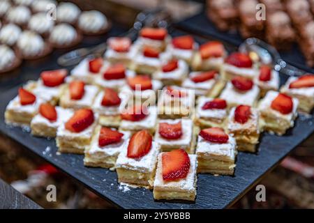 A bakery counter filled with cakes on cake stands. Lots of sweets on a table, variation of pastry products and donuts with chocolate, sugar addiction. Stock Photo