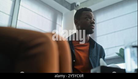Aggressive African American man loses self control, starts quarrel and yells during couples therapy. Multiethnic family having conflict on counseling session with therapist or marriage counselor. Stock Photo