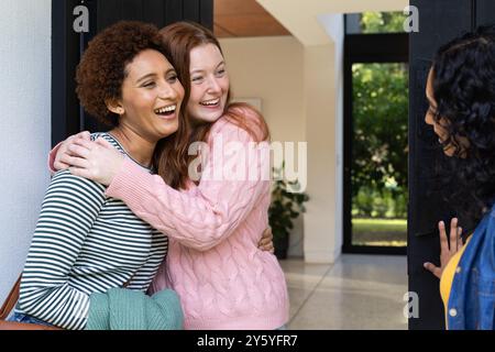 Hugging and smiling, two women friends greeting each other at home entrance Stock Photo