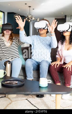 Using VR headsets, diverse women friends experiencing virtual reality together on couch Stock Photo
