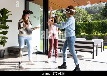 Using VR headsets, diverse women friends enjoying virtual reality experience together Stock Photo