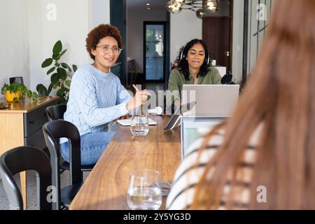 Taking notes and using laptop, women friends enjoying time together at home Stock Photo