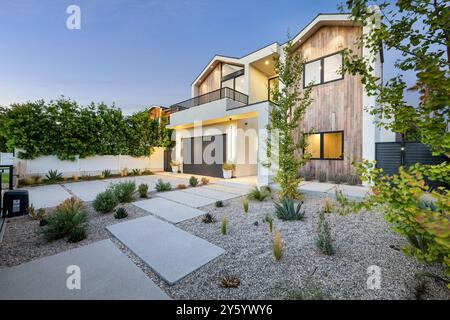 Front garden of a modern minimalist house with stone pillars, a hedge ...