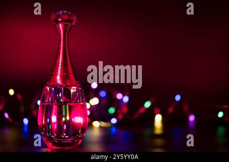 a bottle of perfume on a black background illuminated with colored lights Stock Photo