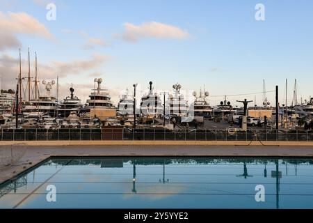 View of the swimming pool of the Rainier III Nautical Stadium with luxury yacht moored in Port Hercule, Monte Carlo, Principality of Monaco Stock Photo