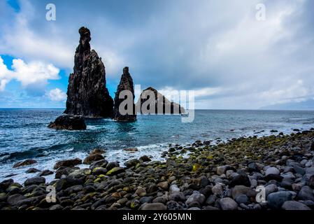 the atlantic ocean crashes on the rocks and coast of Madeira on a cloudy day with calm sea and gray clouds in the North coast of Madeira near Seixal M Stock Photo