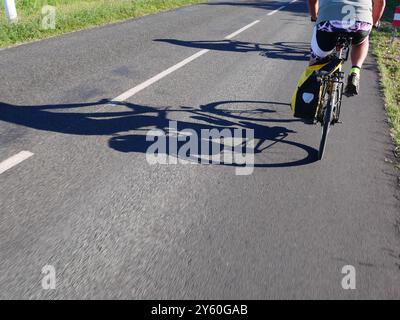 Cyclists on holiday in France cast shadows on the road they are riding along. Stock Photo