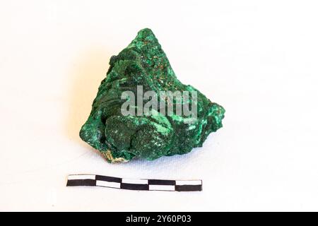 A sample of dark green Malachite on a white background with a 5cm scale. Stock Photo