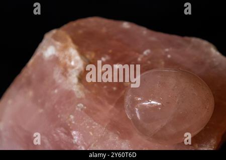 Close-up of a Rose Quartz tumble stone, on top of a rough massive quartz sample Stock Photo