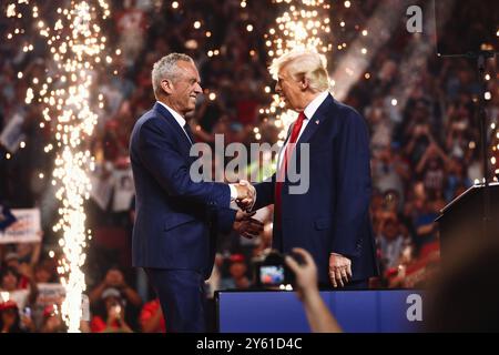 Glendale, Arizona, USA - 23 August 2024: Robert F. Kennedy, Jr. and Donald Trump shaking hands and smiling at a political campaign rally in an arena f Stock Photo