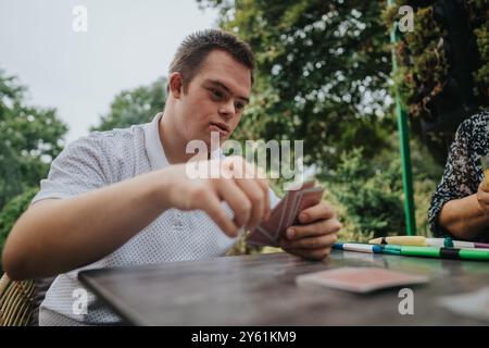 Young man with Down syndrome playing cards outdoors Stock Photo