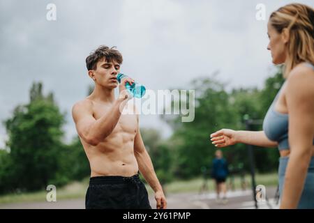 Fit man and woman taking a break and hydrating during outdoor workout Stock Photo